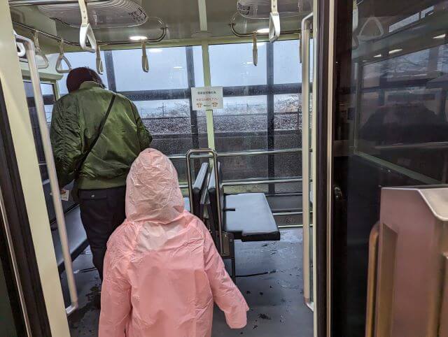 大分県にある高崎山自然動物園の雨の日にカッパを着てケーブルカーに乗る女の子と父親