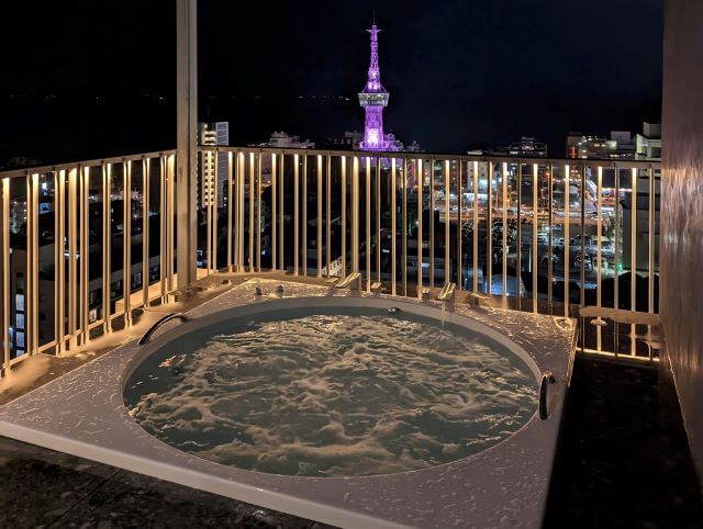 大分県別府市にある「アマネク別府ゆらり」の最上階にあるインフィニティープール横のジャグジーから別府タワーを眺める画像。夜景。