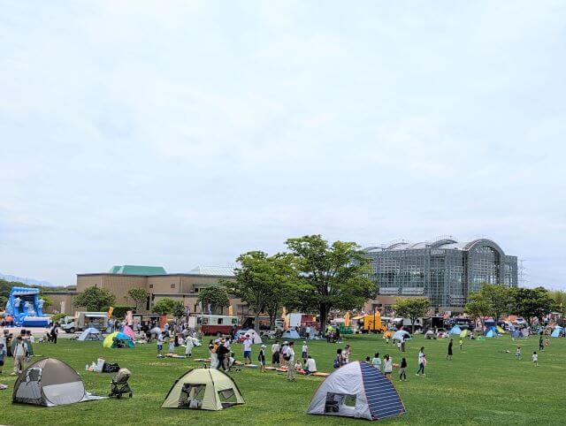 福岡県北九州市にある「響灘グリーンパーク」の大芝生広場の賑わう人々とテントの画像
